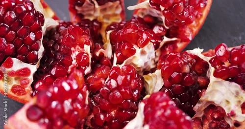 Ripe pomegranate on a dark wooden background. Slow motion.
