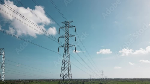 Aerial drone view of a newly constructed electric transmission tower on a green rice field