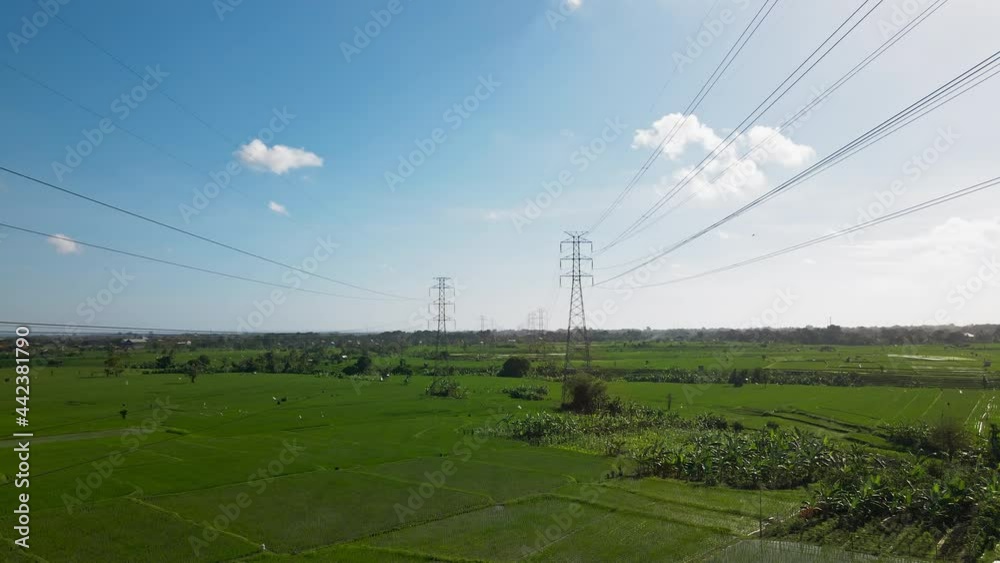 Aerial drone view of a newly constructed electric transmission tower on a green rice field Aerial drone view of a newly constructed electric transmission tower on a green rice field