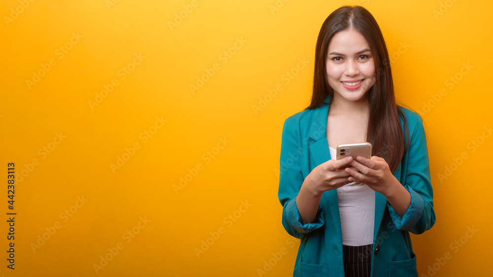 Fashion portrait of beautiful woman in green suit using cellphone on yellow background Fashion portrait of beautiful woman in green suit using cellphone on yellow background