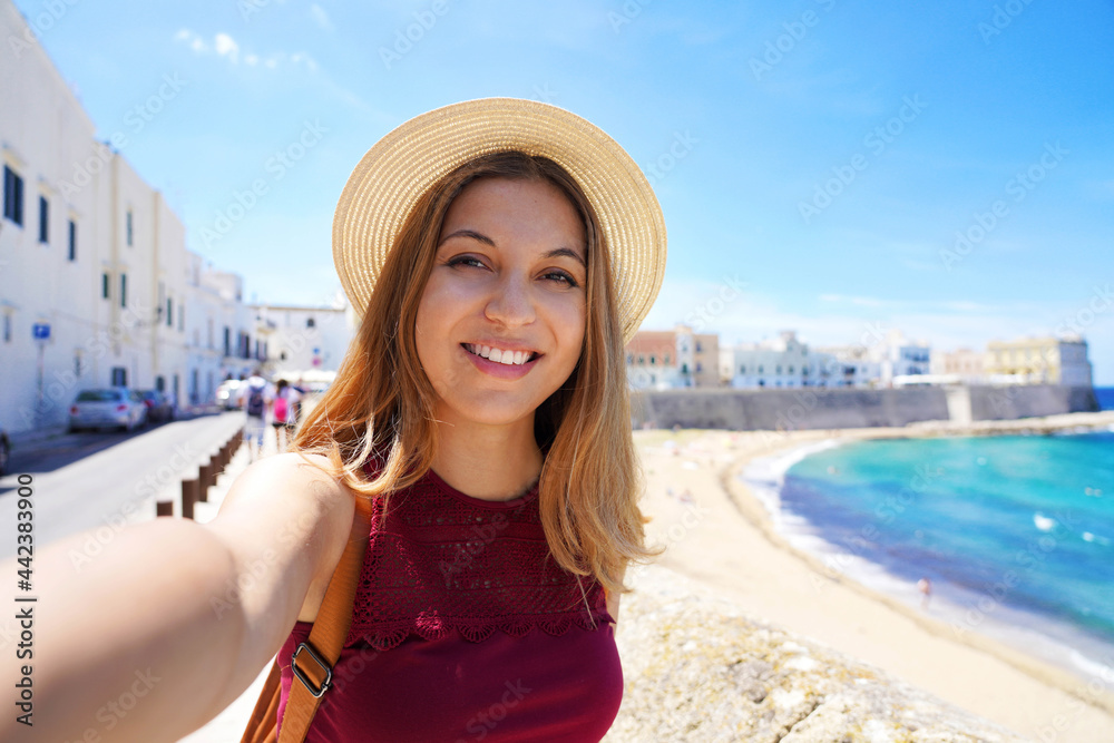 Happy young woman taking self picture by smartphone capturing moments on summer vacations trip