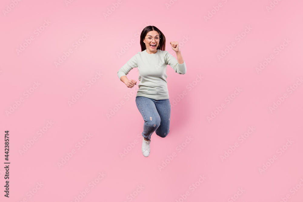 Full size photo of attractive excited happy lady jump up runner you isolated on pastel pink color background Full size photo of attractive excited happy lady jump up runner you isolated on pastel pink color background