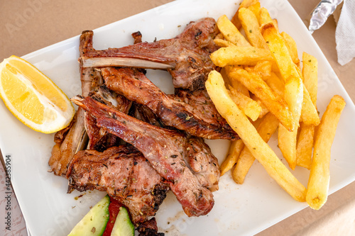 Obraz na płótnie Grilled lamb chops served with fries in restaurant. Traditional Greek dish. w salonie
