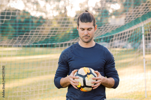 man standing on the field while looking down holding a soccer ball