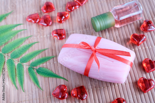 Pink soap, red hearts on a wooden background. Concept for natural use of funds. Valentine's Day, love for spa
