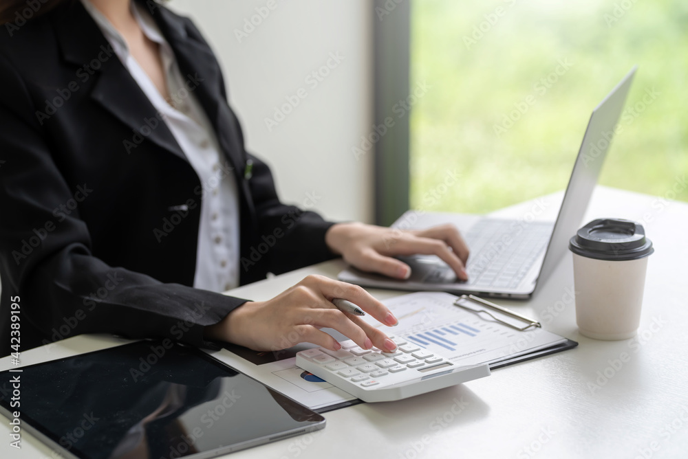 Close-up of businesswoman hand using a calculator with a laptop to calculate at the office. Close-up of businesswoman hand using a calculator with a laptop to calculate at the office.
