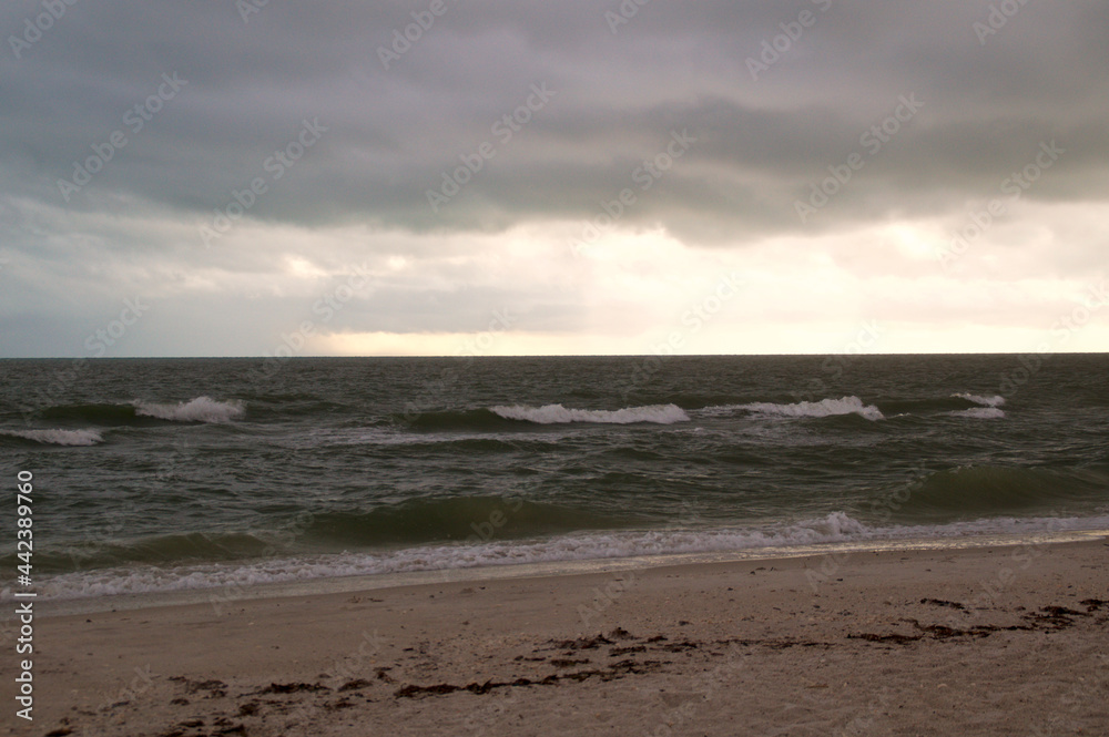 Thick heavy storm clouds fill the sky over the gulf of Mexico in bonita springs, Florida, as waves crash on bonita beach.