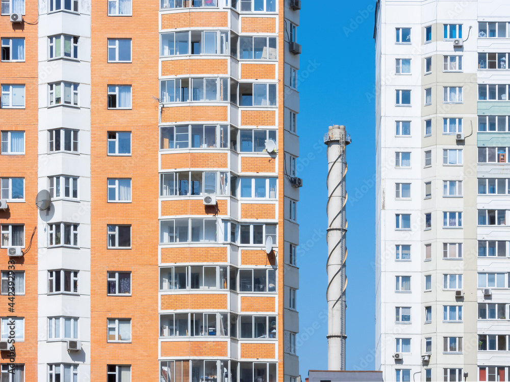 Chimney tube against a blue sky surrounded by apartment buildings Chimney tube against a blue sky surrounded by apartment buildings