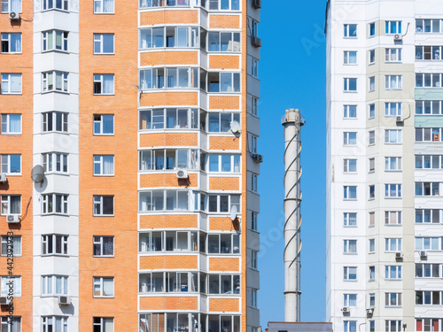 Chimney tube against a blue sky surrounded by apartment buildings © RISHAD