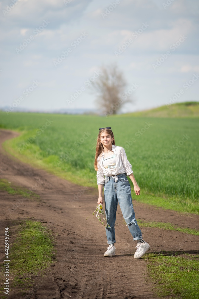 fashionable little girl in a field on a path, against a background of clouds fashionable little girl in a field on a path, against a background of clouds