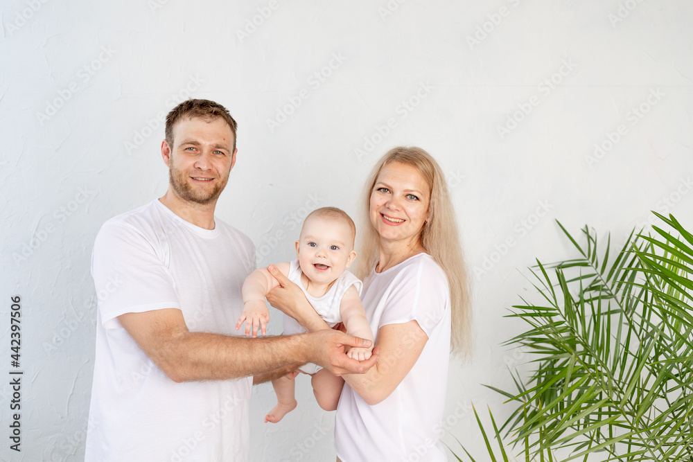 happy family mother and father hold baby in their arms while playing and having fun at home