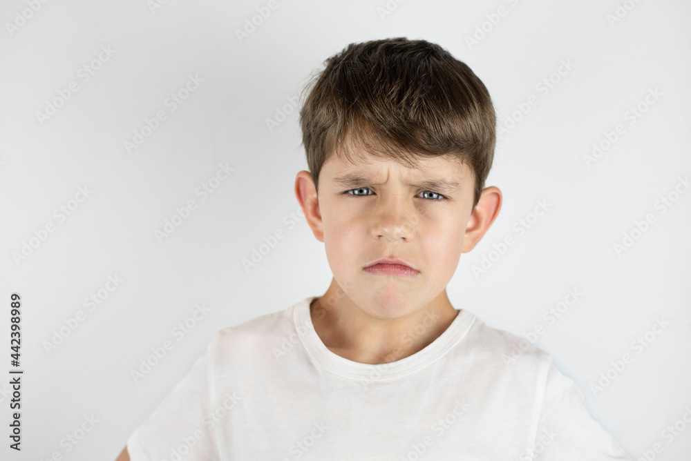 A young boy in a bright T-shirt on a light background with emotions of anger and sadness, the boy was offended by children in kindergarten and he feels lonely. Concept against bullying A young boy in a bright T-shirt on a light background with emotions of anger and sadness, the boy was offended by children in kindergarten and he feels lonely. Concept against bullying