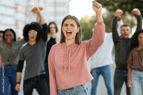 Closeup of young lady leader over demonstrators making riot outdoors