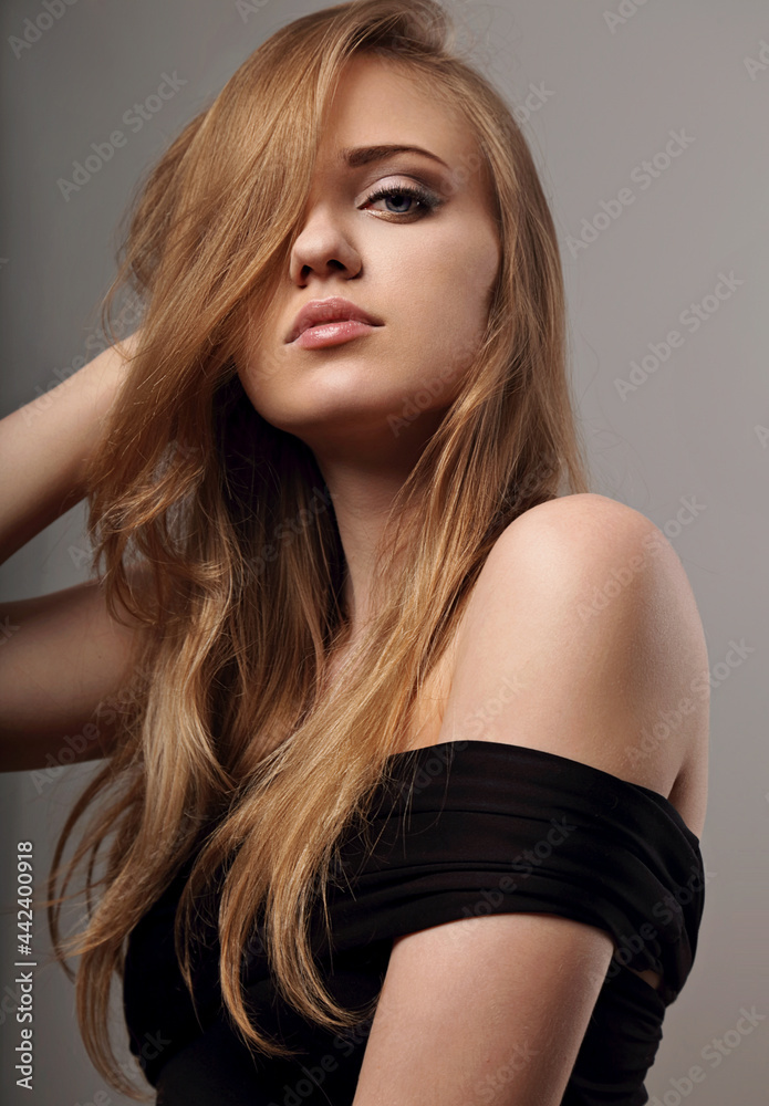 Beautiful natural makeup woman with long blond hair style in black dress, pink lipstick looking on grey background.. Closeup glamor Beautiful natural makeup woman with long blond hair style in black dress, pink lipstick looking on grey background.. Closeup glamor
