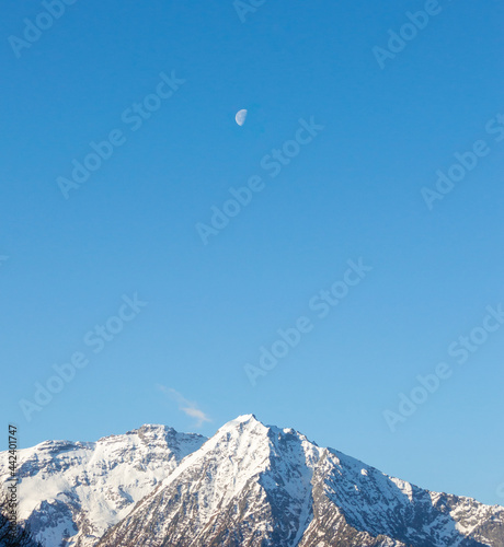 Minimal mountain peak landscape with the moon in the blu clear sky