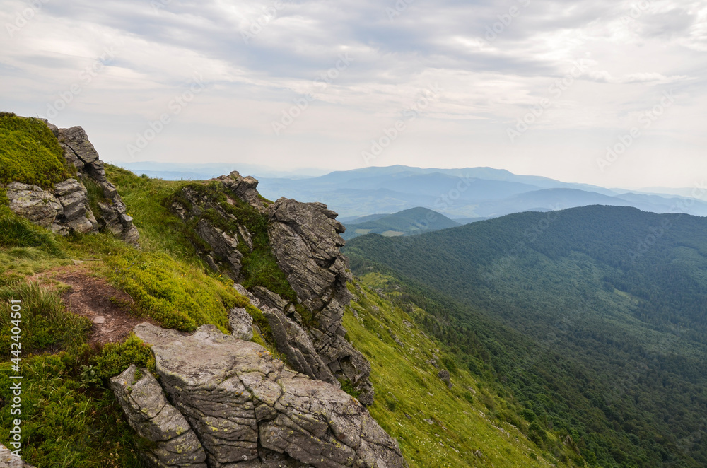 Mountain peak with boulders and forested hills on background at summer day. Pikuj mount, Carpathian mountains, Ukraine