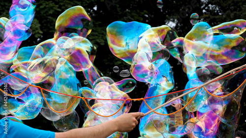 a man makes large and long soap bubbles against the background of green trees. a holiday for children