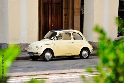 Yellow retro mini car parked on a city street.