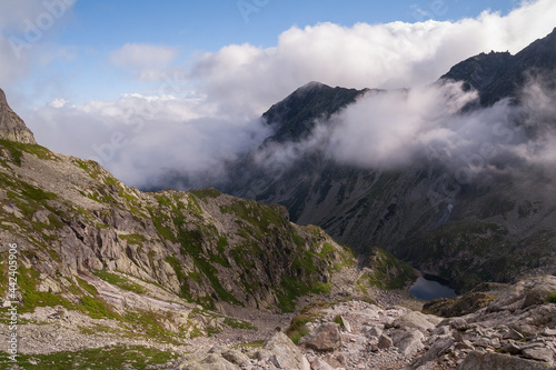 Magnificent mountain lake with peaks half covered in clouds in the high tatras.