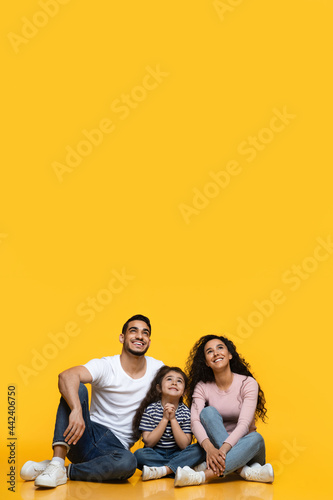 Interesting Offer. Smiling Middle-Eastern Family Of Three Looking Up At Copy Space