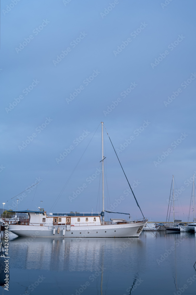 Yacht and boats parking in harbor. White sailing yachts at the pier. Sea yacht club. Aegean sea. Athens, Greece. Twilight. Yacht and boats parking in harbor. White sailing yachts at the pier. Sea yacht club. Aegean sea. Athens, Greece. Twilight.