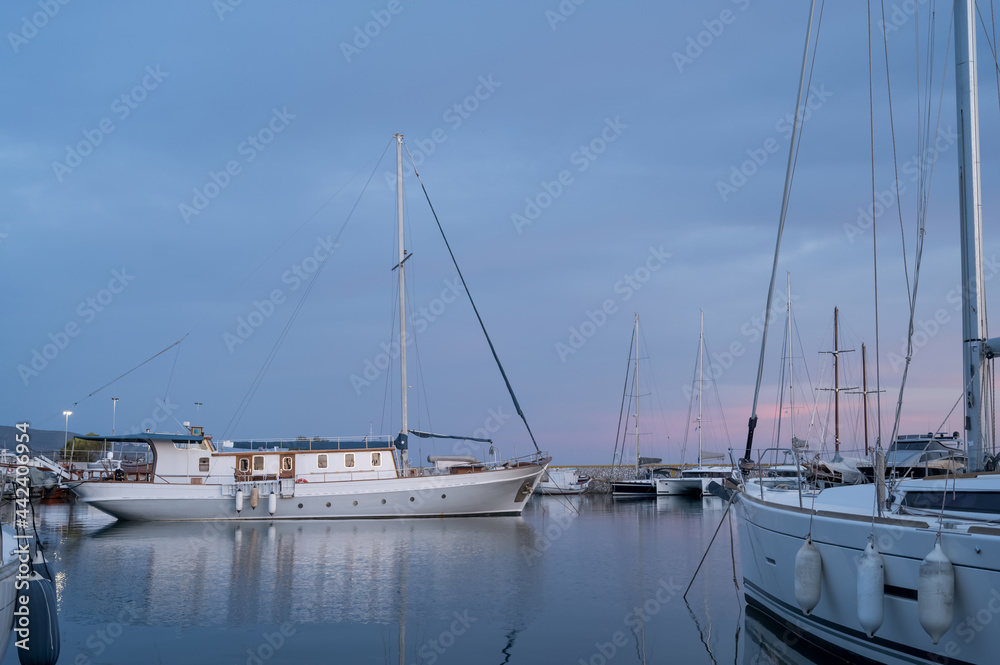 Fototapeta premium Yacht and boats parking in harbor. White sailing yachts at the pier. Sea yacht club. Aegean sea. Athens, Greece. Twilight.