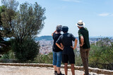 Una familia de tres turistas contemplando las vistas de una ciudad en verano desde un mirador. Barcelona ciudad desde lo alto de una colina.