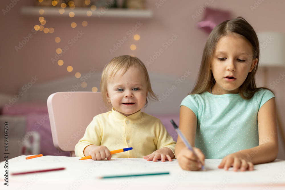 two children draws at the table in the room, two children draws at the table in the room,