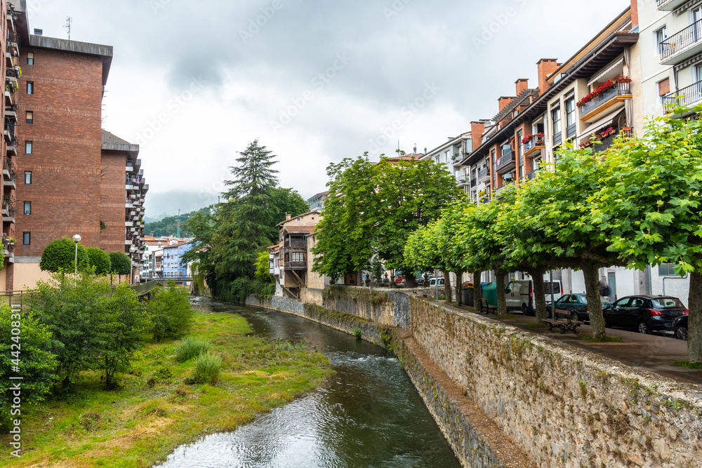 Traditional houses in the town of Azkoitia next to the Urola river and Church of Santa María La Real in the background, Gipuzkoa. Basque Country