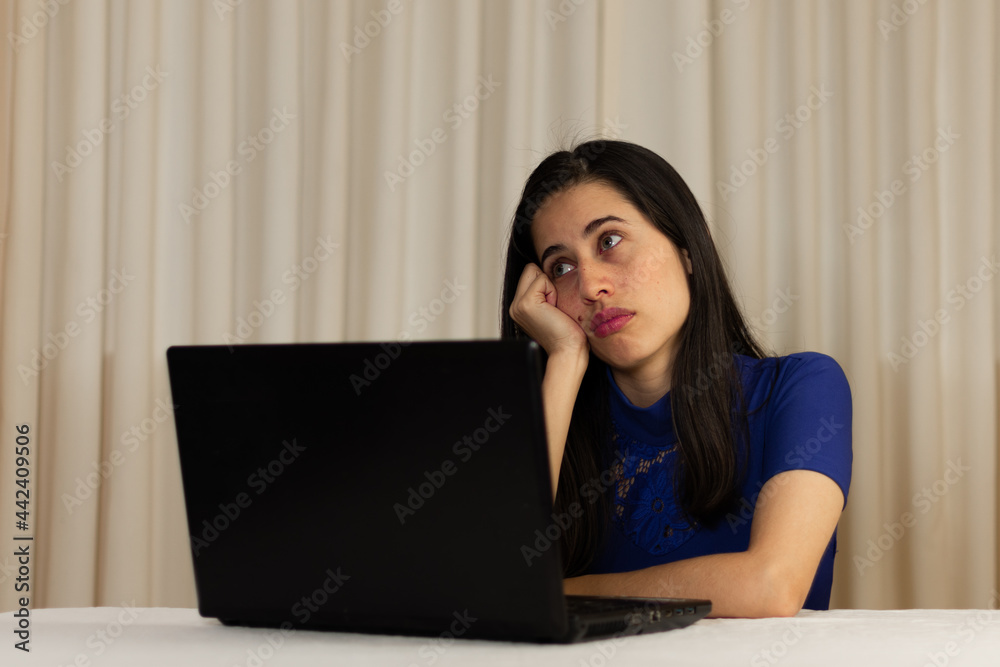 Woman sitting in front of her laptop. staring at the screen, bored, sleepy, tired. Latin woman in front of her laptop without spirits. Woman sitting in front of her laptop. staring at the screen, bored, sleepy, tired. Latin woman in front of her laptop without spirits.
