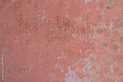 Light red pink concrete wall with cracked peeling paint texture