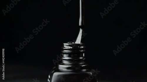 Color gel polish close-up. Drops of gel polish flow down the brush. Black background. 4k footage