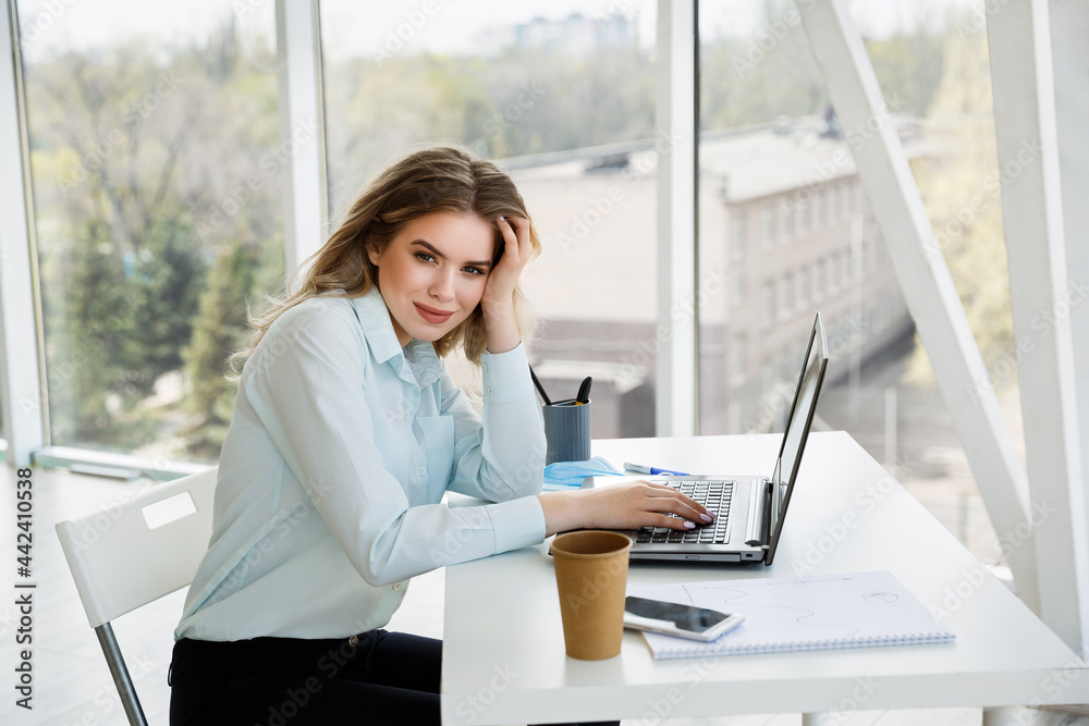 Young beautiful caucasian businesswoman or student works in the modern office with a laptop Young beautiful caucasian businesswoman or student works in the modern office with a laptop