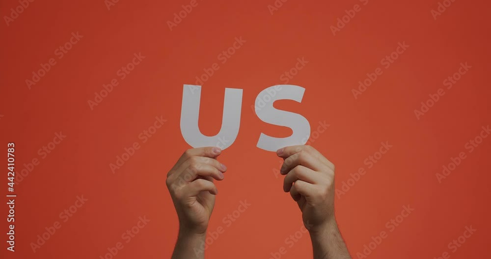 Hands raising up showing word US. Man shows United States sign made of carved paper for blog Hands raising up showing word US. Man shows United States sign made of carved paper for blog