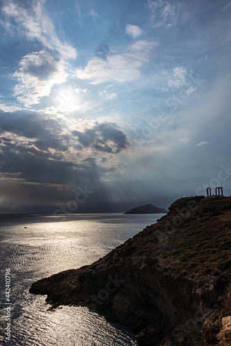 Sunset over the Temple of Poseidon at Cape Sounion, Greece. Cliff with dramatic view on mediterranean sea and ruins of an ancient Greek temple with Doric-style columns. Vertical