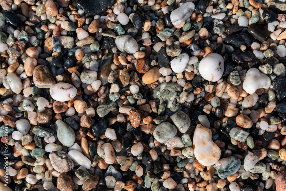 Aegean sea pebble marble stone beach close-up texture. Various rocky surface in sunny Greece near Athens. Top view