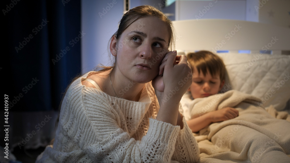 Young woman crying at bed of her sick son at night Young woman crying at bed of her sick son at night