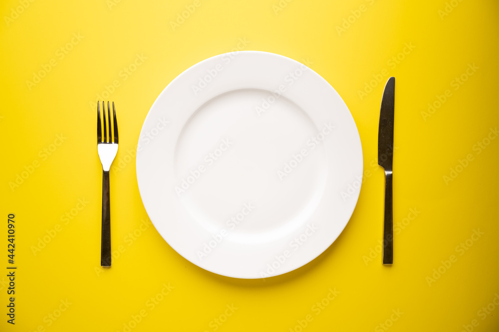 knife, fork and plate on yellow background