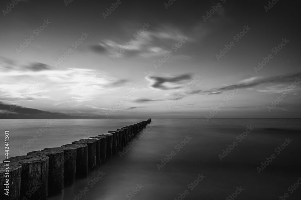 Melancholisch wirkende Landschaft eines Meeres bei Sonnenuntergang in schwarz weiß