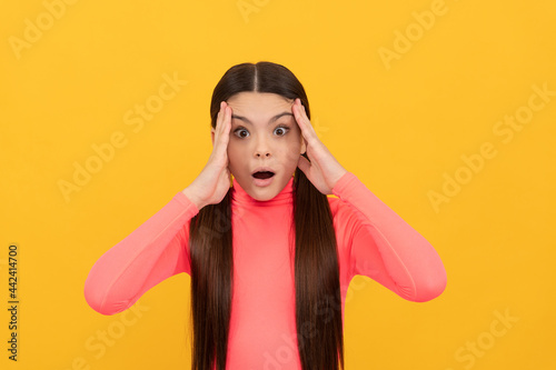shocked teen girl with long hair on yellow background, emotions