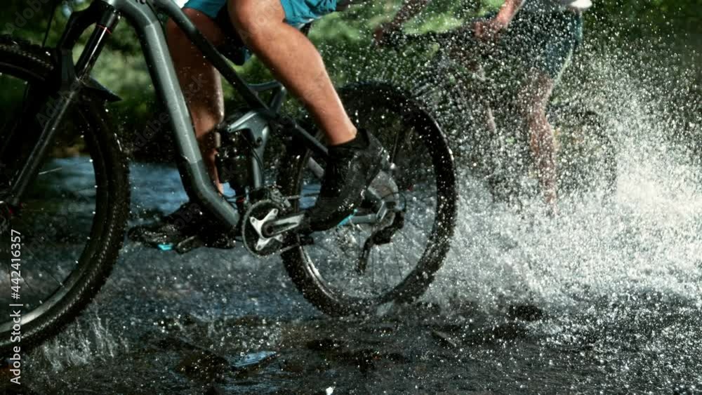 Super slow motion of mountain biker passing a river. Speed ramp effect. Filmed on high speed cinema camera, 1000 fps.