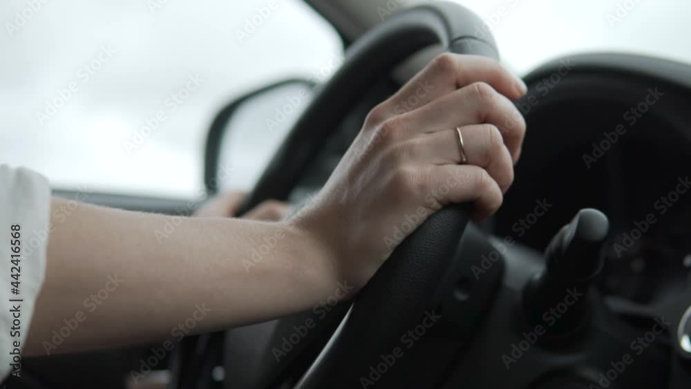 A close-up of hands on the steering wheel, a woman drives a car. A close-up of hands on the steering wheel, a woman drives a car.