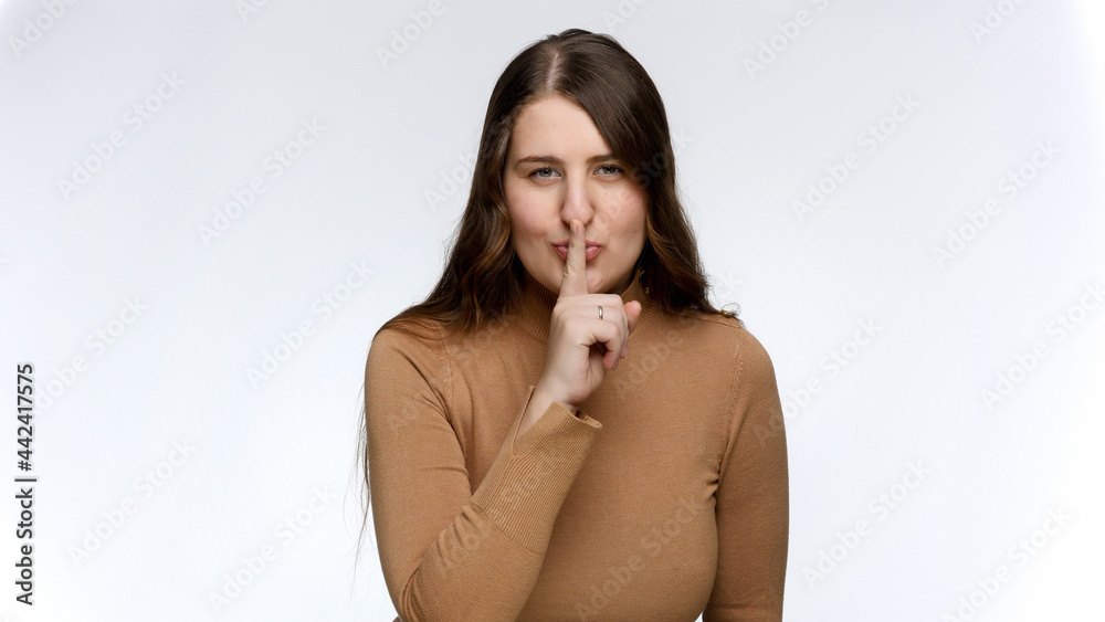 Portrait of smiling woman flirting and putting finger at lips. Concept of keeping secret and silence Portrait of smiling woman flirting and putting finger at lips. Concept of keeping secret and silence