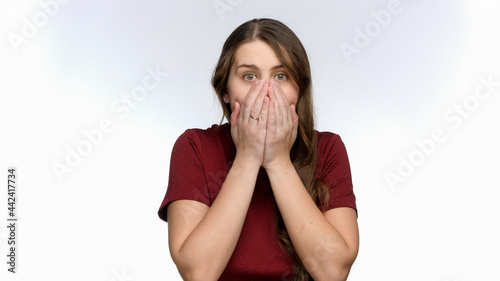 Happy smiling woman gets surprised closing mouth with hands.