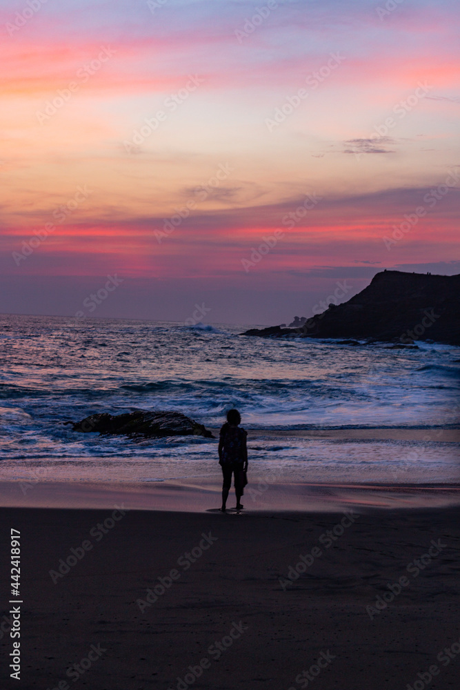 a girl meditates on the cloudy landscape during a colorful sunset on the beach. back light landscape