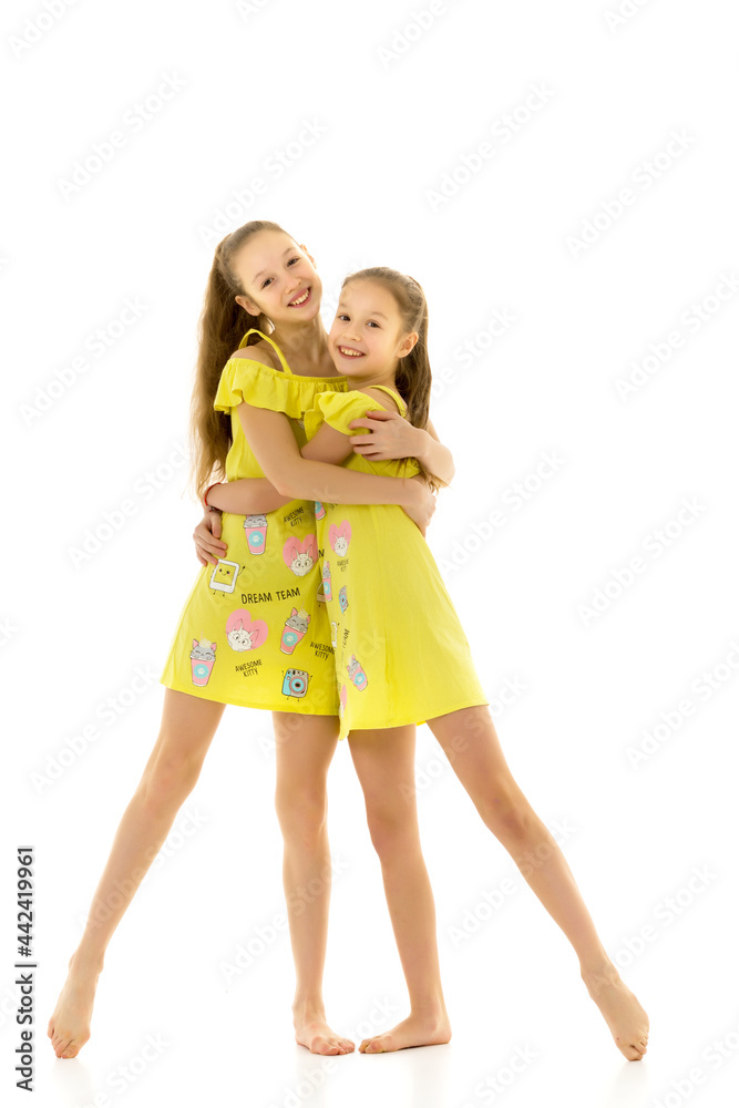 Two Happy Teen Girls Sisters in Yellow Dresses Hugging and Smili