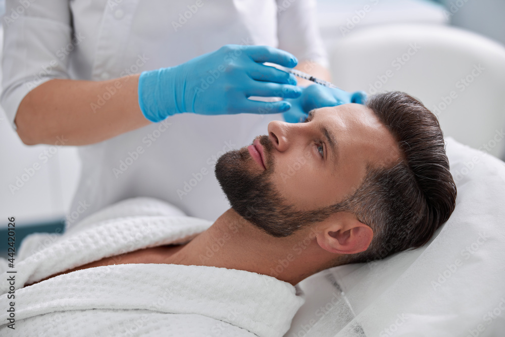Φωτογραφία Lady cosmetologist holds syringe with filler above forehead of middle aged patie