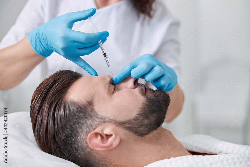 Middle aged patient grimaces of pain undergoing eyebore lifting procedure in clinic Middle aged patient grimaces of pain undergoing eyebore lifting procedure in clinic