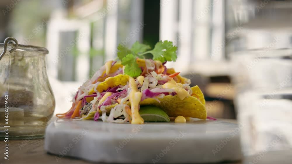 Caucasian man taking taco into his hand. Beautiful and bright mexican dish on a exquisite marbel plate. Latin American cuisine in a cafe outdoors. 4K 120 fps slow motion video shot with macro food 