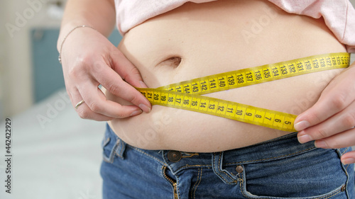 Photography Closeup of young woman loosing weight measuring her waist